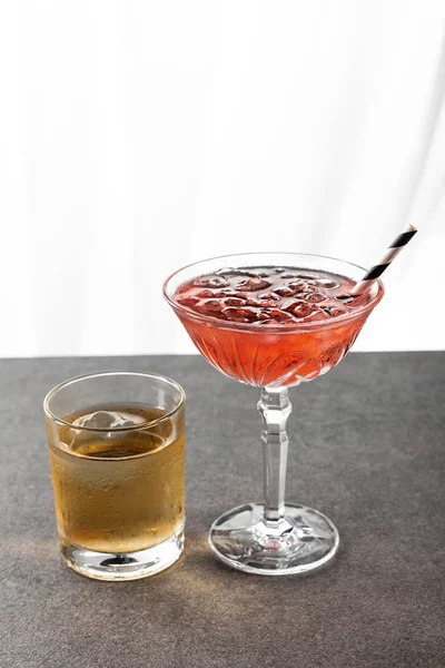 Verre mouillé avec whisky près de cocktail cosmopolite rouge sur blanc — Photo de stock