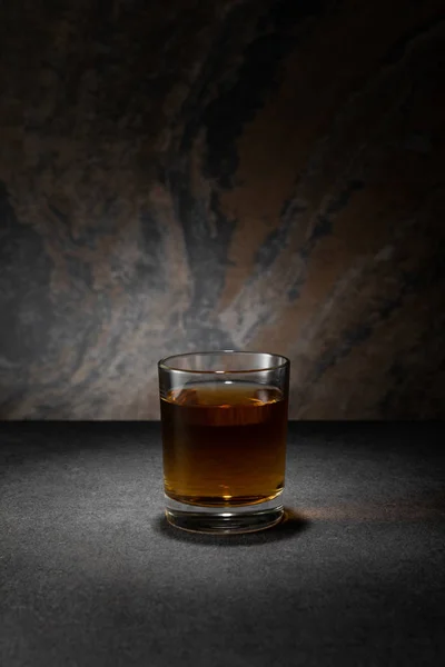 Cognac in glass on textured granite background — Stock Photo