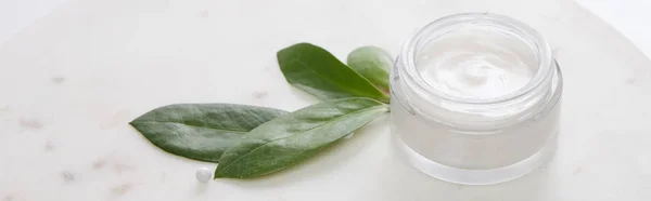 Cosmetic cream with leaves and decorative bead on white background, panoramic shot — Stock Photo