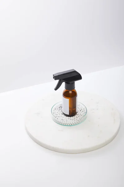 Vue grand angle du flacon distributeur d'huile cosmétique à l'intérieur de la verrerie de laboratoire avec perles décoratives isolées sur gris — Photo de stock