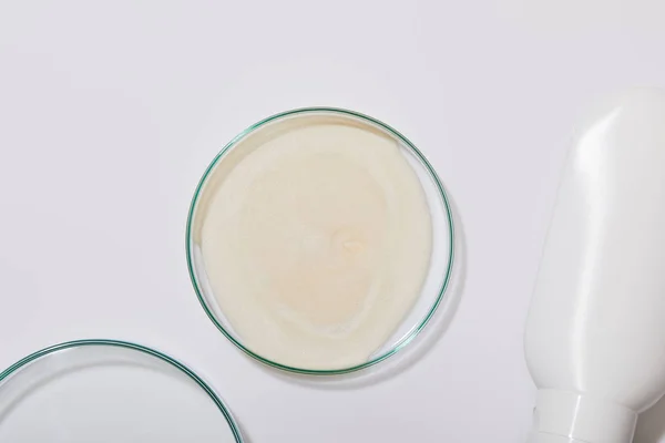 Visão superior da amostra de creme cosmético em vidro laboratorial ao lado do tubo em fundo cinza — Fotografia de Stock