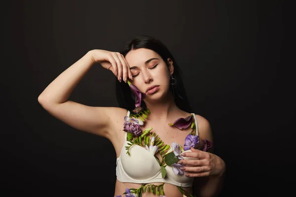 Tender beautiful girl in bra with violet and purple flowers on body isolated on black — Stock Photo