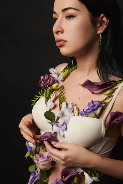 Belle fille en soutien-gorge avec des fleurs violettes et violettes sur le corps isolé sur noir — Photo de stock
