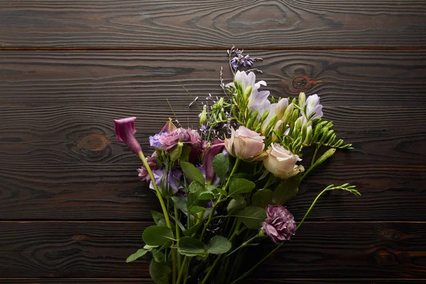 Вид на фиолетовый и фиолетовый цветочный букет на деревянный стол — стоковое фото