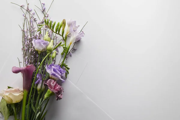 Vue du dessus du bouquet violet enveloppé dans du papier sur fond blanc — Photo de stock