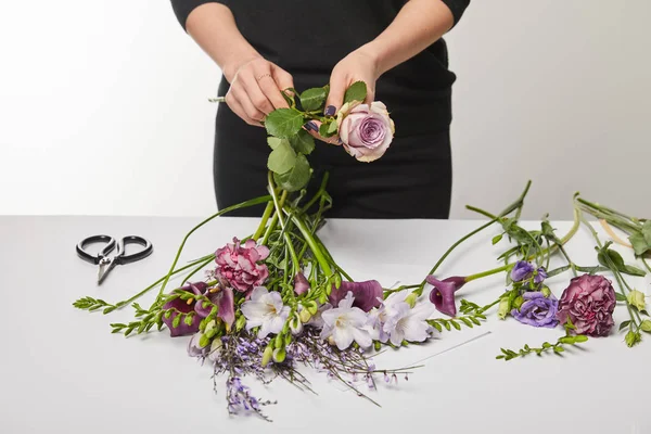 Vista recortada de florista haciendo ramo violeta aislado en blanco - foto de stock