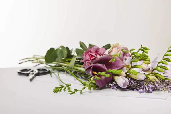 Selective focus of violet and purple flowers near scissors isolated on white — Stock Photo