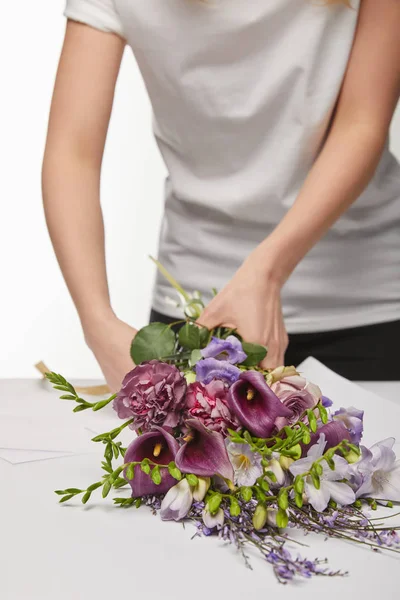 Vista cortada de florista embrulhando buquê violeta em papel isolado em branco — Fotografia de Stock