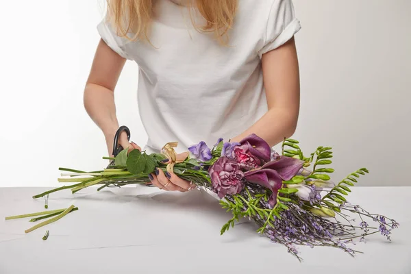 Обрезанный вид на фиолетовый букет, вырезанный флористом с ножницами, изолированными на белом — стоковое фото