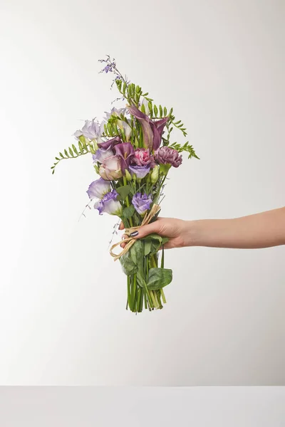 Vista recortada de la mujer sosteniendo ramo de flores violetas y púrpuras en blanco - foto de stock