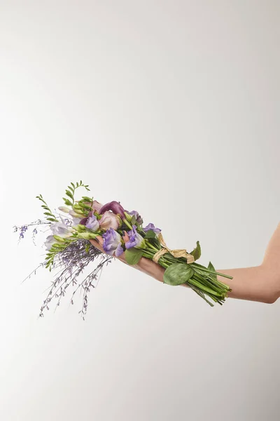 Vista recortada de la mujer sosteniendo ramo de flores violetas y púrpuras en blanco - foto de stock