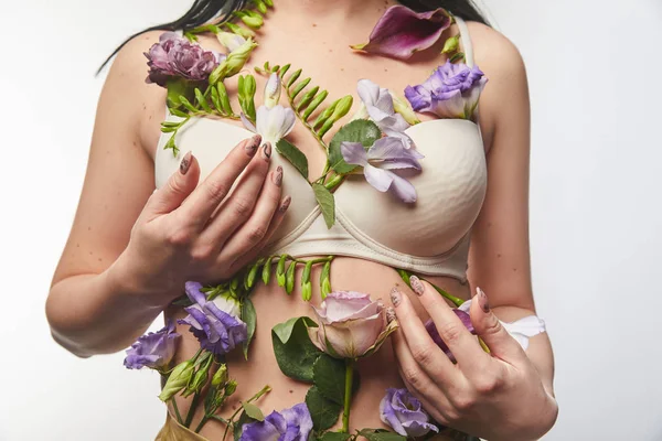 Vue recadrée de fille en soutien-gorge avec des fleurs violettes et violettes sur le corps isolé sur blanc — Photo de stock