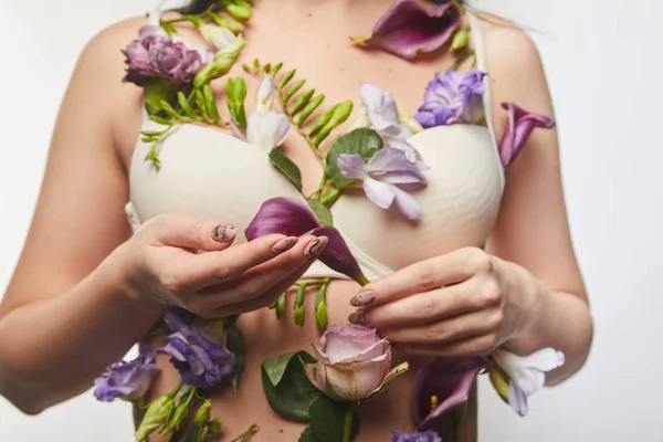 Vue recadrée de fille en soutien-gorge avec des fleurs violettes et violettes sur le corps isolé sur blanc — Photo de stock
