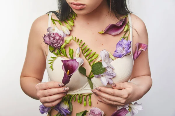 Vue recadrée de fille en soutien-gorge avec des fleurs violettes et violettes sur le corps isolé sur blanc — Photo de stock