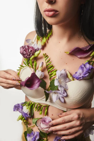 Vue recadrée de fille en soutien-gorge avec des fleurs violettes et violettes sur le corps isolé sur blanc — Photo de stock