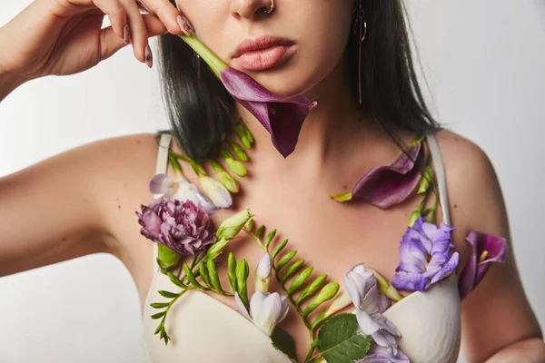 Vue recadrée de fille en soutien-gorge avec des fleurs violettes et violettes sur le corps tenant calla isolé sur blanc — Photo de stock