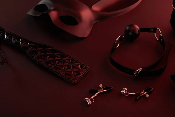 Секс-игрушки при темном освещении на красном фоне — стоковое фото