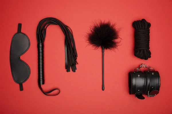 Flat lay with various black sex toys isolated on red — Stock Photo