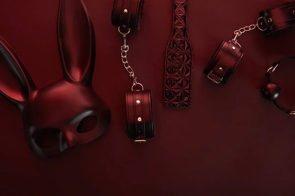 Ansicht von Sexspielzeug in dunkler Beleuchtung auf rotem Hintergrund — Stockfoto