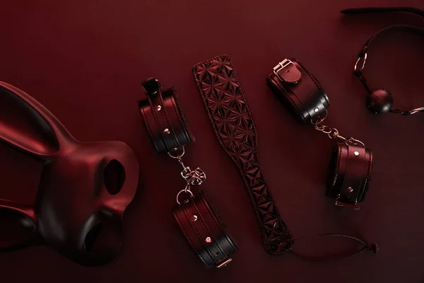 Vista superior de los juguetes sexuales en la iluminación oscura sobre fondo rojo - foto de stock