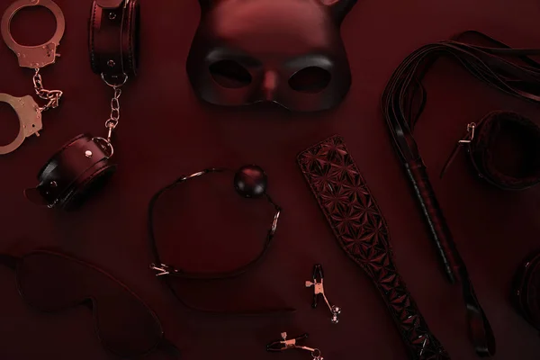 Ansicht von Sexspielzeug in dunkler Beleuchtung auf rotem Hintergrund — Stockfoto