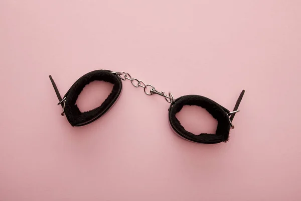 Top view of black handcuffs on pink background — Stock Photo
