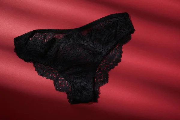 Vue de dessus de culotte femelle noire sur fond rouge — Photo de stock