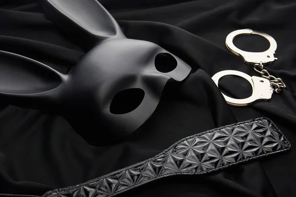 Rabbit mask and sex toys on black textile background — Stock Photo