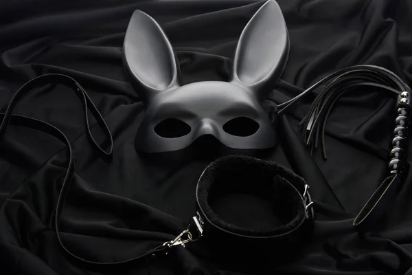 Rabbit mask and sex toys on black textile background — Stock Photo