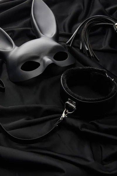 Rabbit mask and sex toys on black textile background — Stock Photo