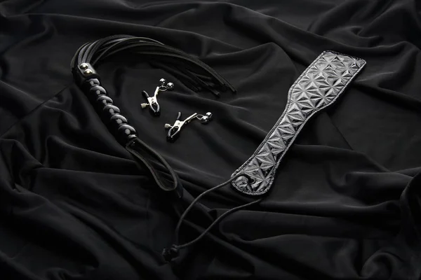 Leather and metal sex toys on black textile background — Stock Photo