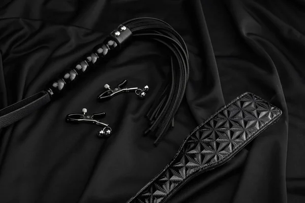 Juguetes sexuales de cuero y metal sobre fondo textil negro - foto de stock
