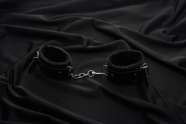 Leather handcuffs on black textile background — Stock Photo