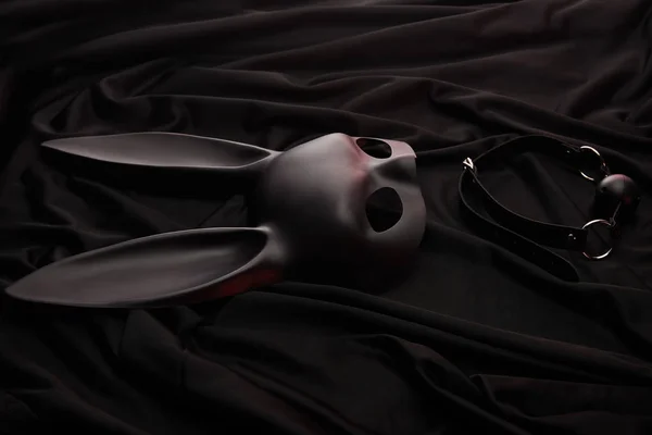 Rabbit mask and gag on black textile background — Stock Photo