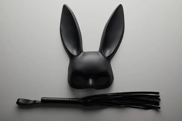 Top view of black rabbit mask and flogging whip on white background — Stock Photo