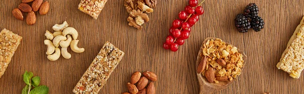 Vista dall'alto di composizione di cibo di bacche, noci e barre di cereali su sfondo di legno, colpo panoramico — Foto stock