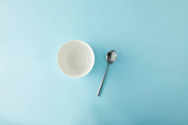 Vue du dessus du bol vide et cuillère à café sur fond bleu — Photo de stock