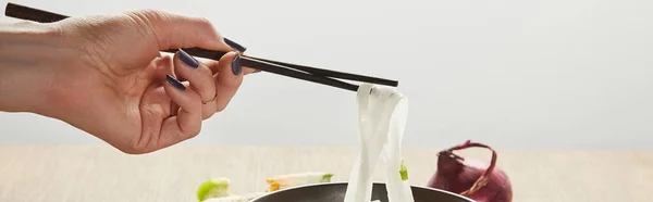 Cropped view of woman eating rice noodles isolated on grey, panoramic shot — Stock Photo