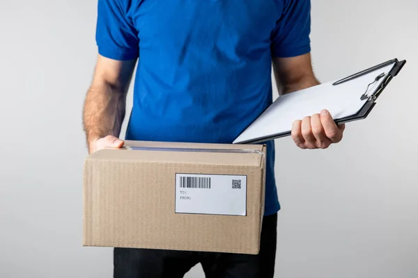 Cropped view of courier holding clipboard and cardboard box isolated on grey — Stock Photo