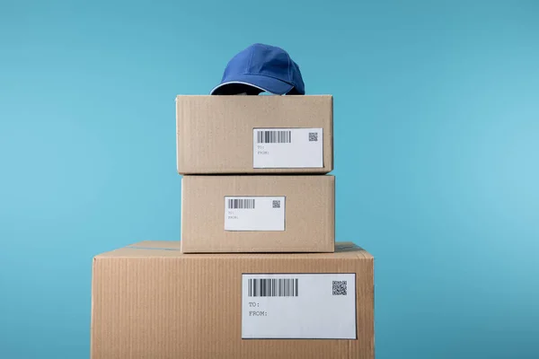 Cap on stacked cardboard boxes isolated on blue — Stock Photo