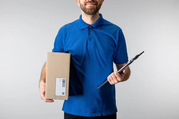 Repartidor de vista recortada hombre sosteniendo caja de cartón y portapapeles aislados en gris - foto de stock