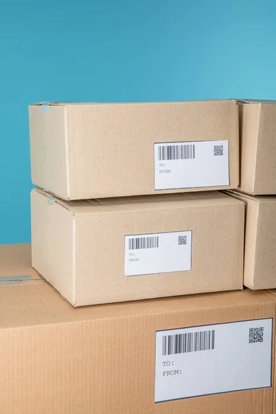 Stacked cardboard packages with barcodes and qr codes isolated on blue — Stock Photo