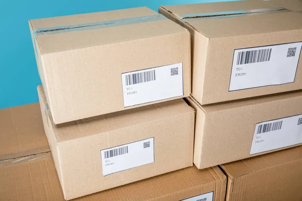 Stacked cardboard boxes with qr and barcodes on cards isolated on blue — Stock Photo