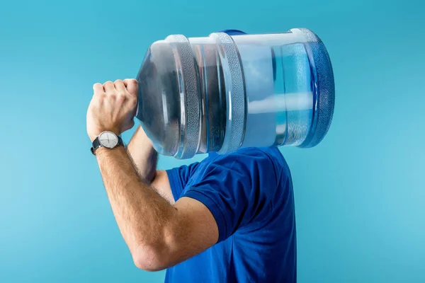 Side view of courier holding bottled water isolated on blue — Stock Photo