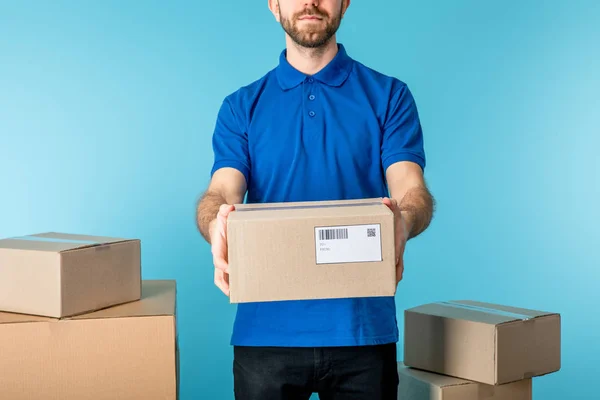 Abgeschnittene Ansicht des Kuriers mit Pappverpackung in der Nähe von Schachteln isoliert auf blau — Stockfoto