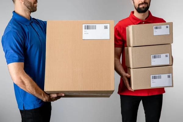 Vista recortada dos correios que detêm caixas de cartão isoladas a cinzento — Fotografia de Stock