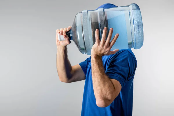 Vista lateral del mensajero llevando en el hombro botella de agua aislada en gris - foto de stock