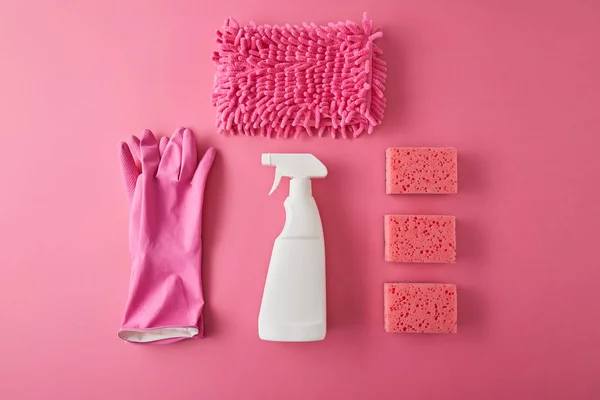 Flat lay com frasco de spray, esponjas, pano e luvas de borracha para limpeza da casa em rosa — Fotografia de Stock