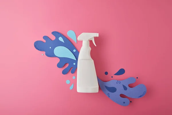 Composition with spray bottle and blue water splashes made of paper, on pink — Stock Photo