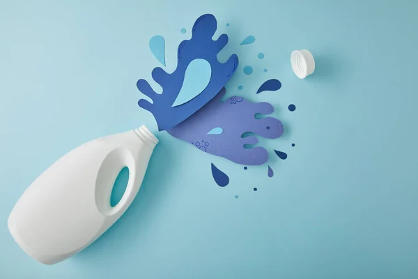 Top view composition with bottle and water splashes made of paper, on blue — Stock Photo